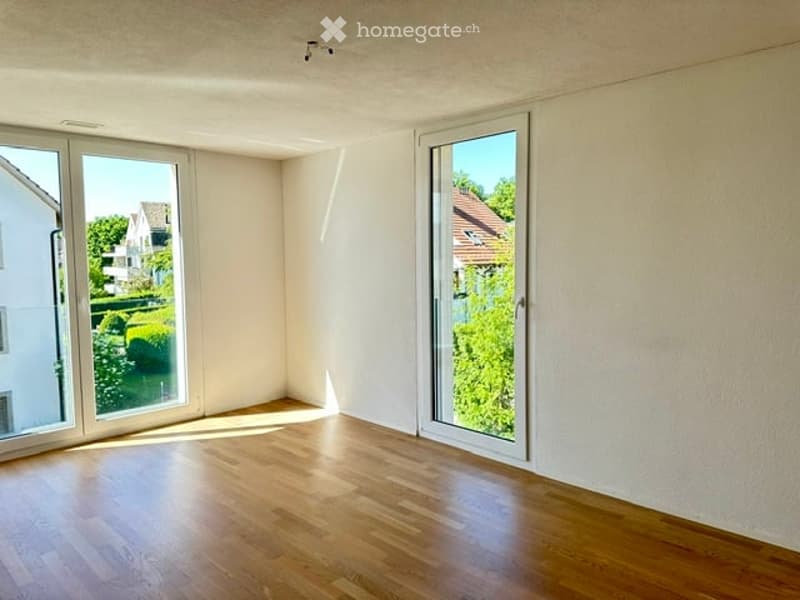 Empty room with wooden flooring, large windows, and white walls. No furniture or equipment present.