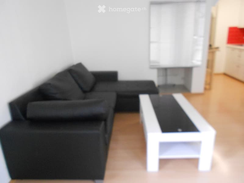 Modern living room with a black sectional sofa, white coffee table, and a table lamp on a side table.