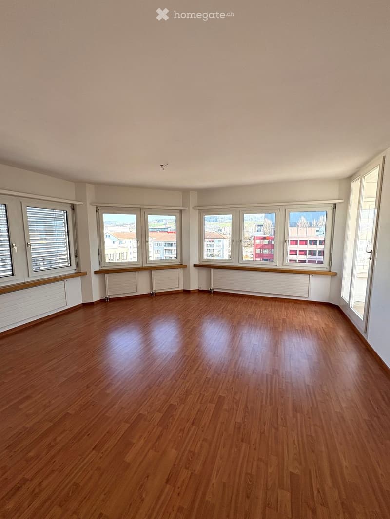 Empty room with wooden flooring, large windows, and radiators. No furniture or equipment present.