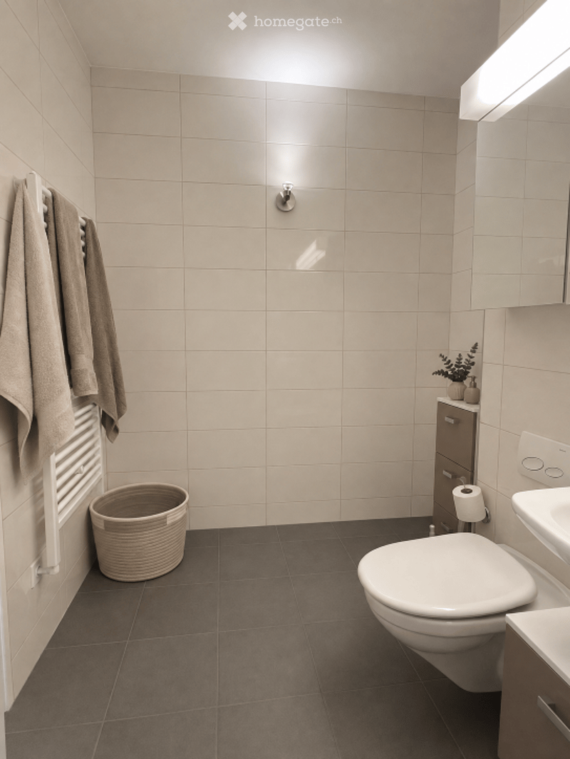 Modern bathroom with beige tiled walls, dark grey tiled floor, white toilet, towel rack with towels, wicker basket, small cabinet with plant, and a sink.