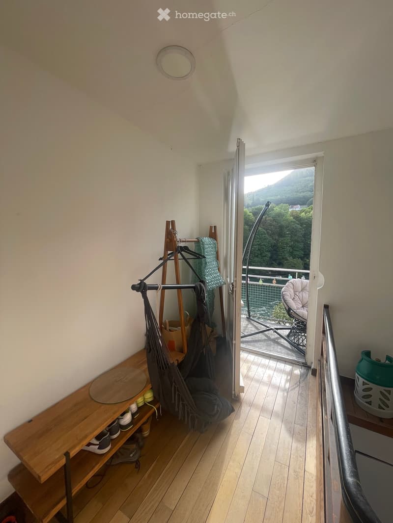 Balcony with wooden floor, railing, chair, and scenic mountain view.