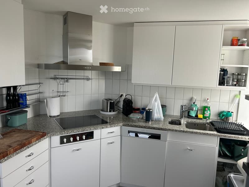 Modern kitchen with white cabinets, granite countertops, stainless steel appliances, and various kitchen items on the counter.