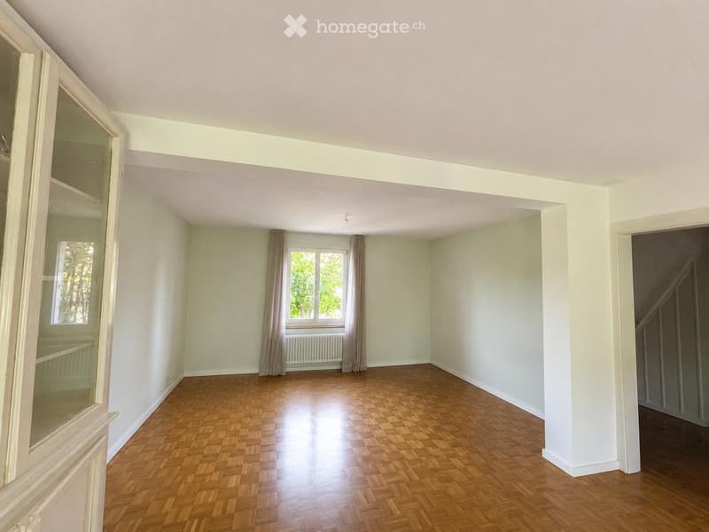 Empty room with wooden flooring, white walls, and large windows with curtains. No furniture or equipment present.