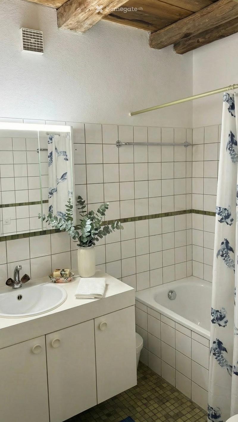 Bathroom with white tiles, white sink, mirror, bathtub, shower curtain, plant, and towel