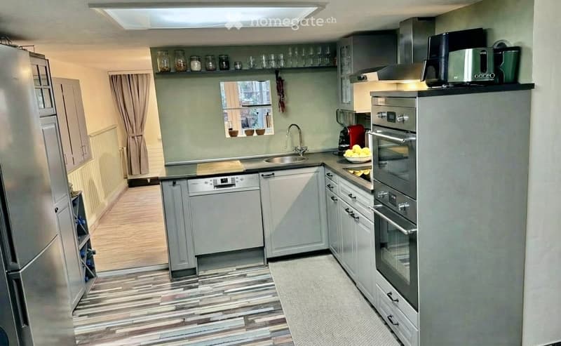 modern kitchen with stainless steel appliances, dishwasher, washing machine, wooden floor, white cabinets, black countertops, built-in oven and microwave