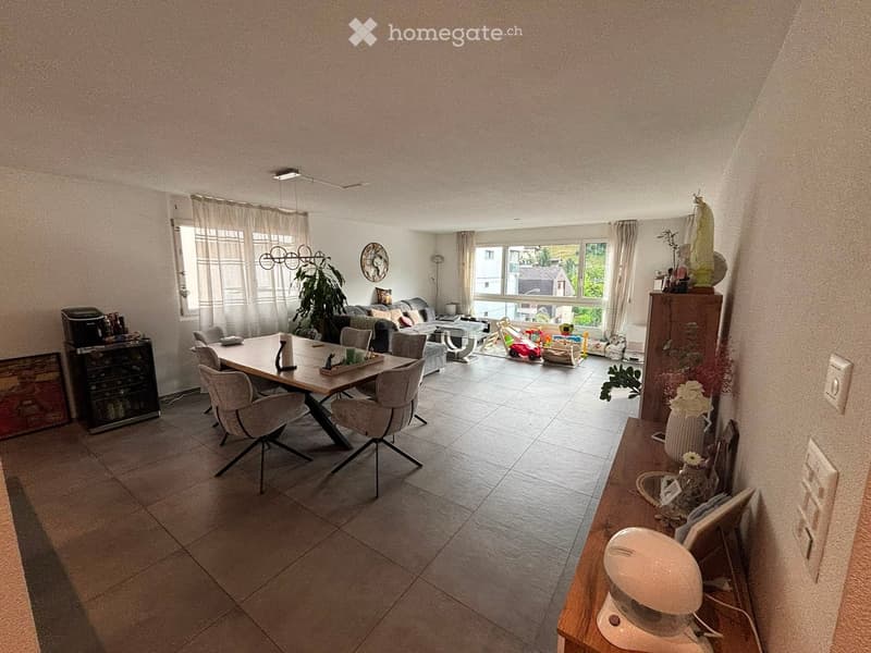 Open-plan living and dining area with a dining table, chairs, sofa, coffee table, and decorative items.