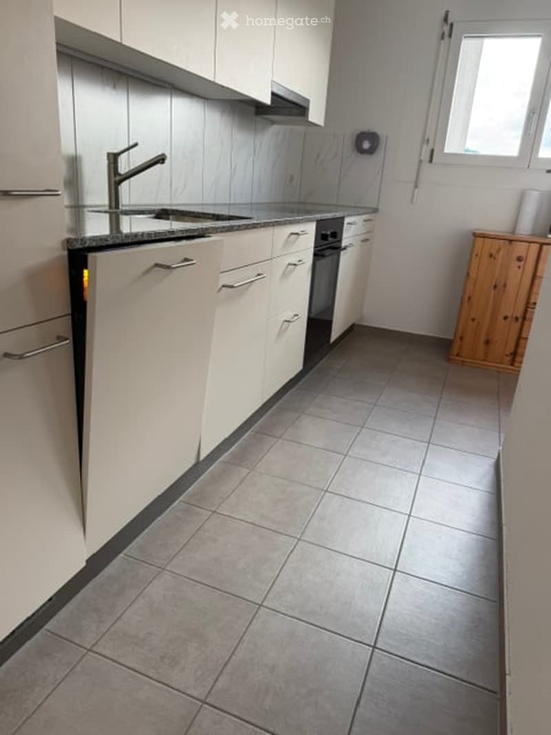 Modern kitchen with white cabinets, stainless steel sink and faucet, tiled floor, and built-in oven and dishwasher.