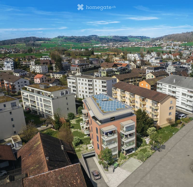 Aerial view of a residential area with multiple apartment buildings, green spaces, and solar panels on rooftops.