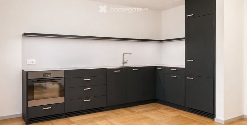 Modern kitchen with dark grey cabinets, stainless steel oven, and a sink with a chrome faucet. The walls are white, and the floor is light wooden.