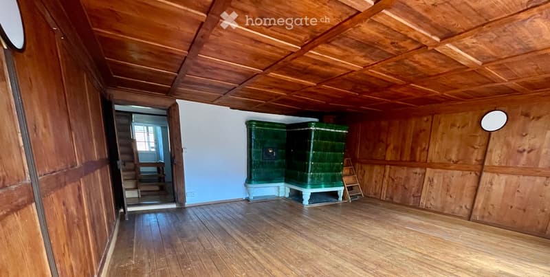 Empty room with wooden walls, ceiling, and floor, featuring two green cabinets and a small staircase leading to another room.
