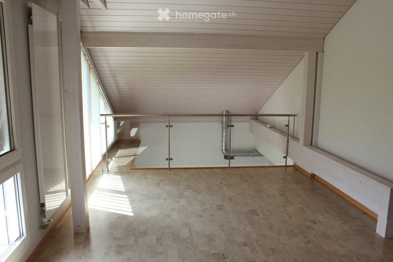 Empty room with wooden ceiling, tiled floor, large windows, and a glass railing leading to another area.