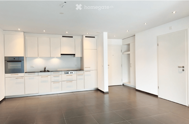 Kitchen. Modern, minimalist kitchen with white cabinets, stainless steel appliances, and a dark tiled floor.