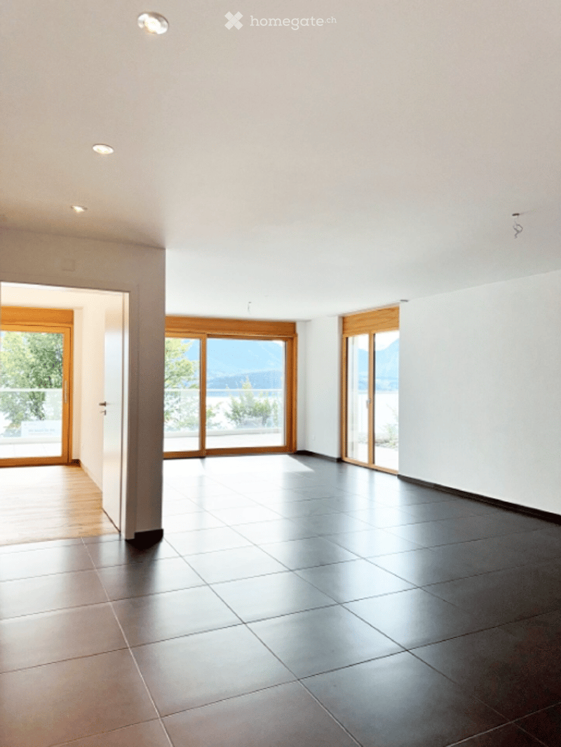 Unfurnished Room. Bright, empty room with large windows and a view, featuring wooden flooring and white walls.