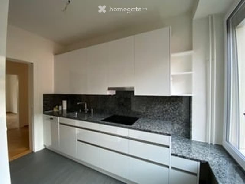 Modern kitchen with white cabinets, granite countertop, and stainless steel sink.