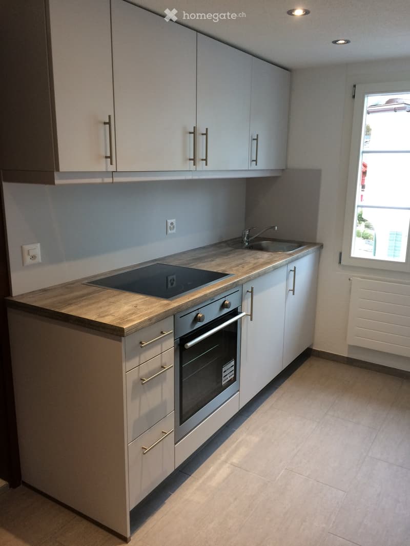 Modern kitchen with white cabinets, wooden countertop, stainless steel oven, sink, and faucet.