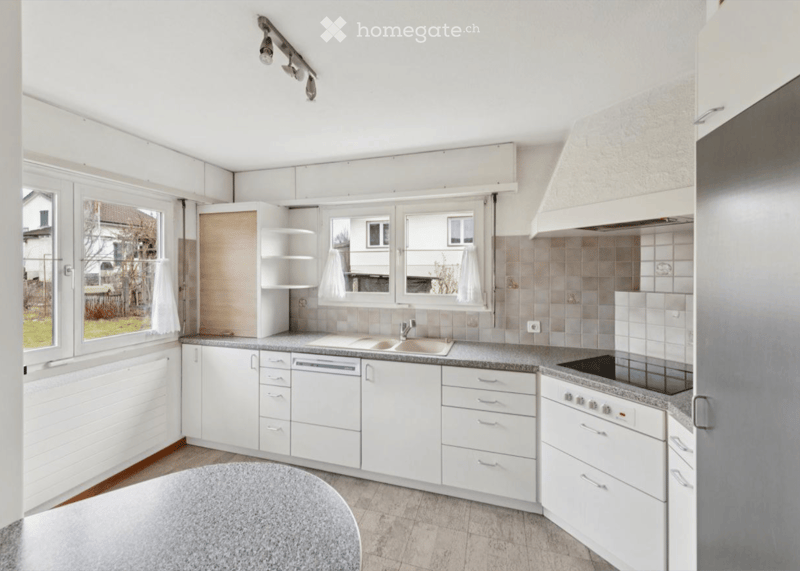 Modern kitchen with white cabinets, granite countertops, stainless steel appliances, and large windows.