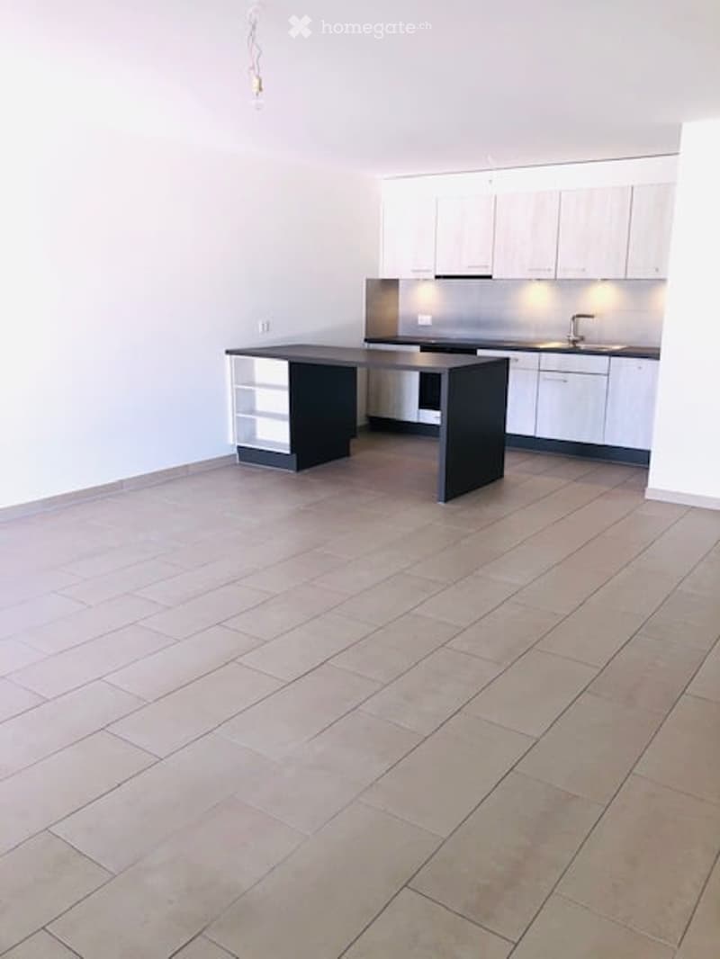 Empty kitchen with black countertop, white cabinets, and tiled floor.