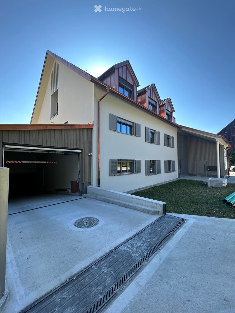 A modern multi-story building with a garage entrance, concrete flooring, and copper roofing