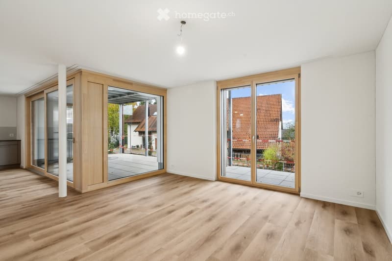 Empty room with wooden flooring, white walls, and large sliding glass doors leading to an outdoor area.