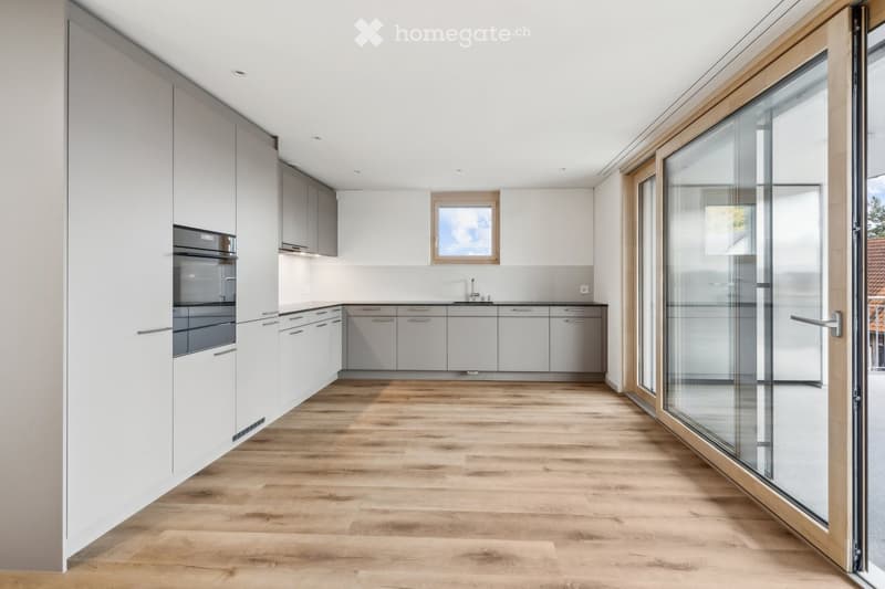 empty kitchen with wooden floor, glass sliding doors, white cupboards, window, modern design