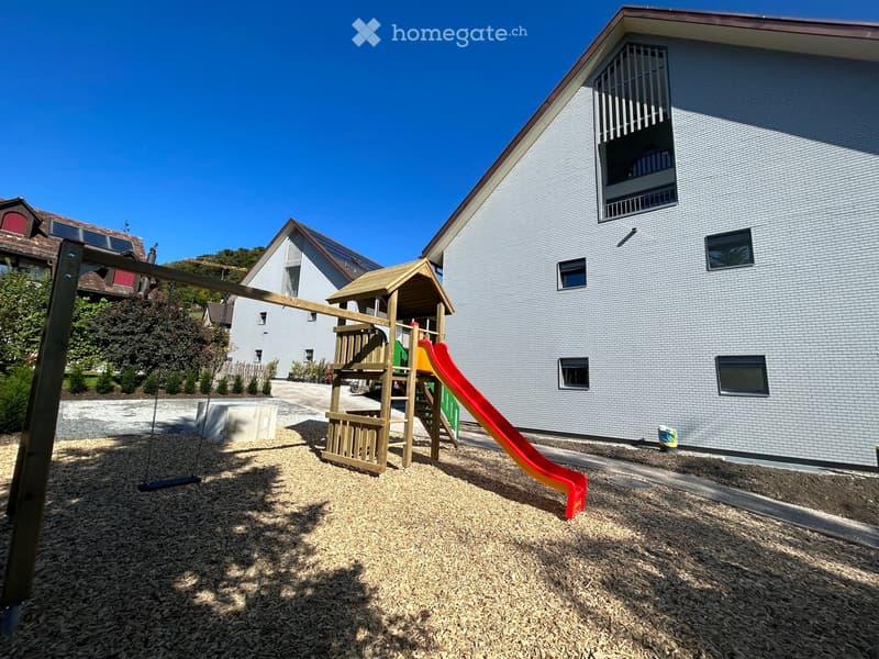 Two story building, tiled wall, two play structures: slide and swing