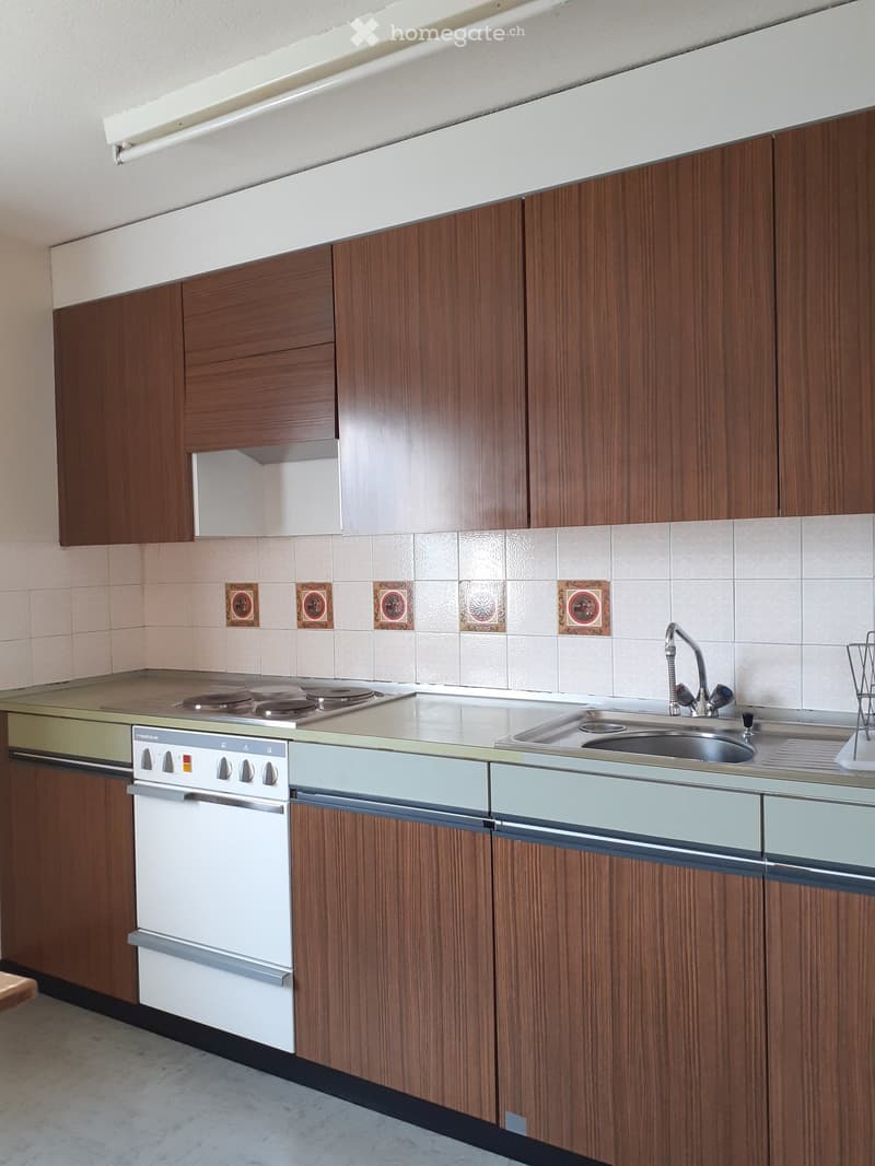 Modern kitchen with wooden cabinets, white oven, stainless steel sink, and countertop.