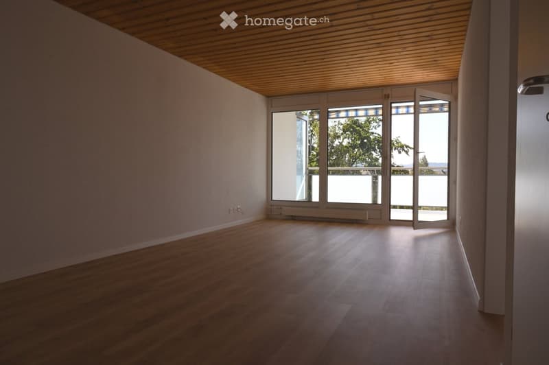 Empty room with wooden flooring, white walls, and large glass doors leading to a balcony.