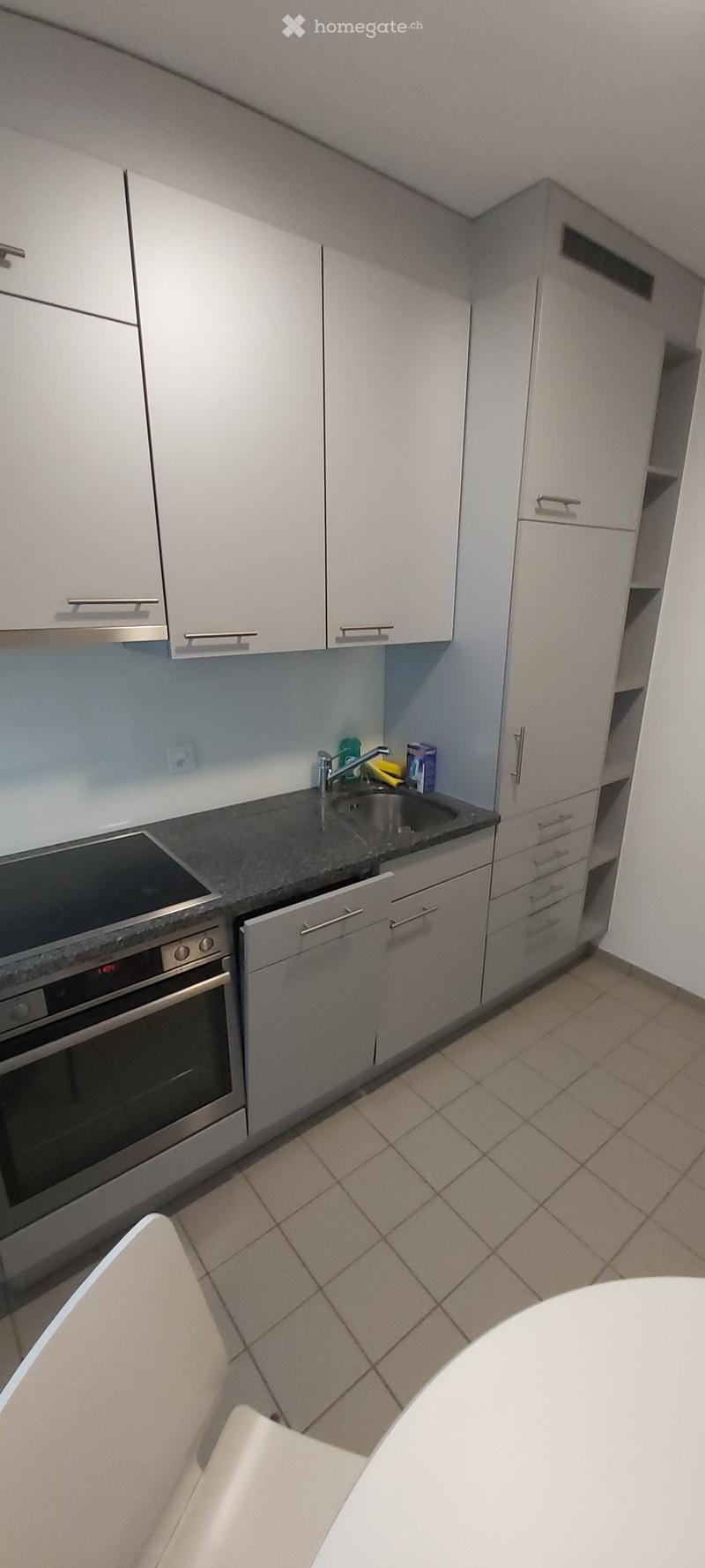Modern kitchen with white cabinets, stainless steel appliances, granite countertop, and tiled floor.