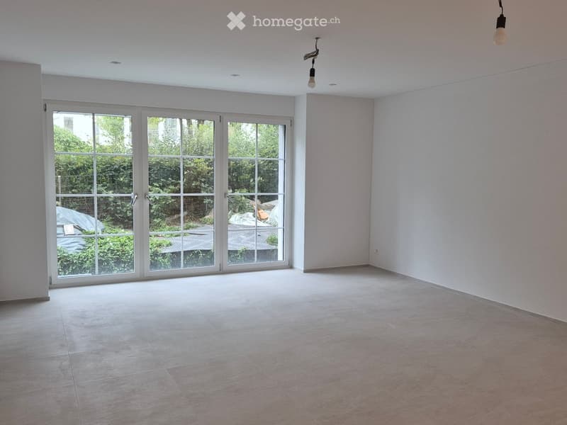 Empty room with light-colored tiled flooring, white walls, and large sliding glass doors leading to an outdoor area.
