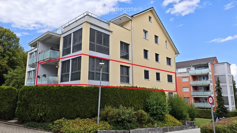 Modern multi-story residential building with balconies, large windows, and a sleek design. The building features a combination of light yellow and white exterior walls, with multiple balconies and a rooftop terrace visible.