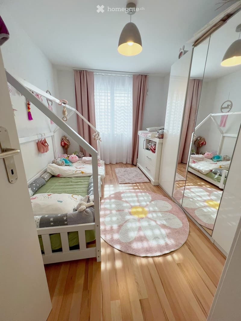 Cozy children's bedroom with bunk bed, mirror, wardrobe, and soft rugs.