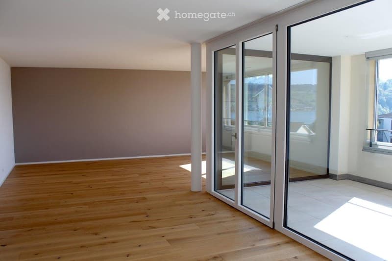 Empty room with wooden flooring, large glass sliding doors, and neutral-colored walls.