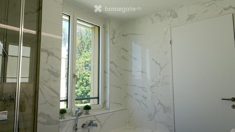 Elegant bathroom with marble walls and floors, a large window, a modern shower enclosure, and a sleek faucet.