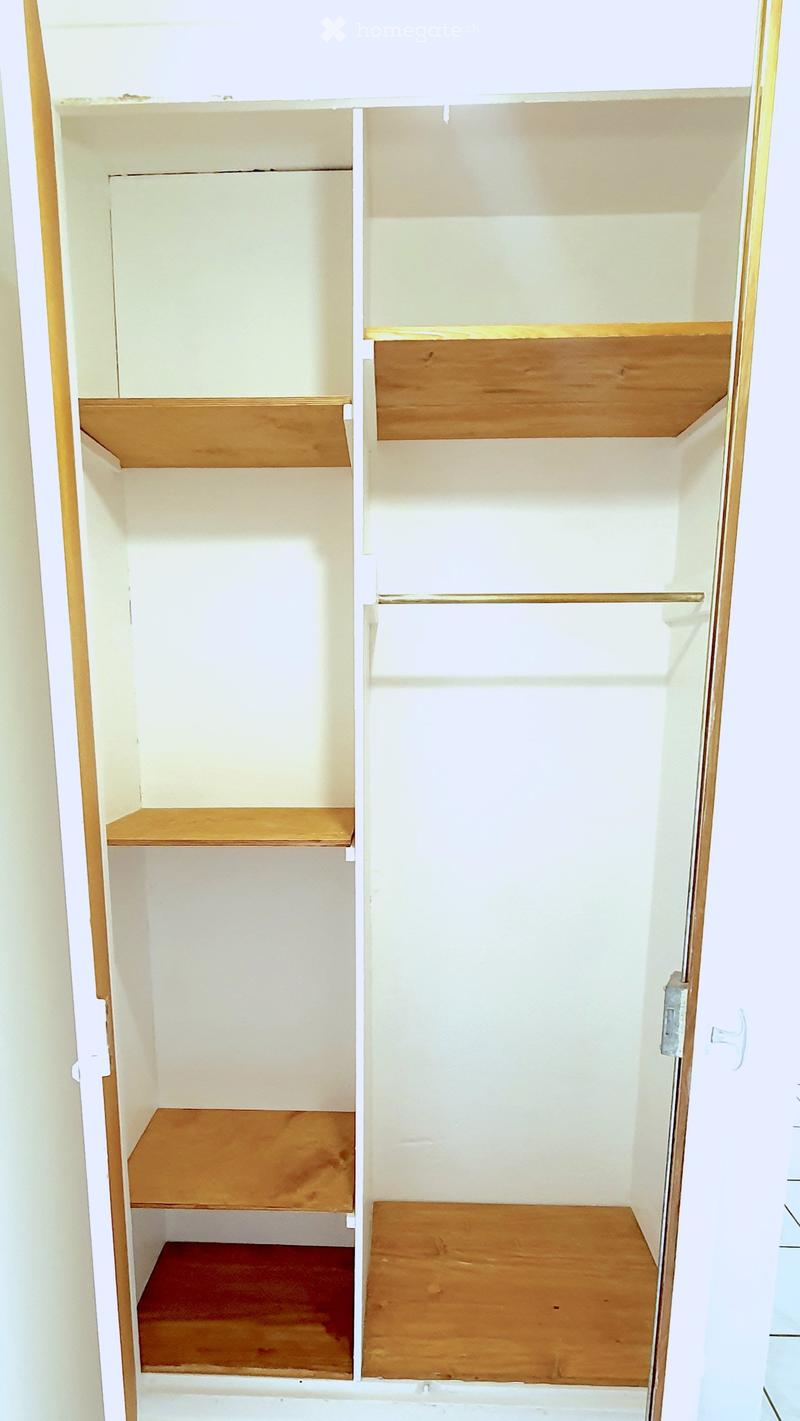 Empty wooden wardrobe with 4 shelves and a hanging rod