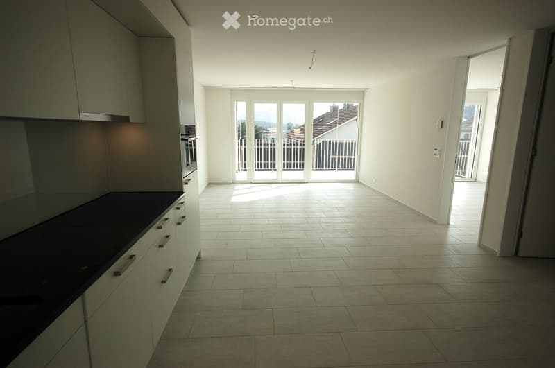 Empty kitchen with white cabinets, dark countertop, and large sliding glass doors leading to a balcony.