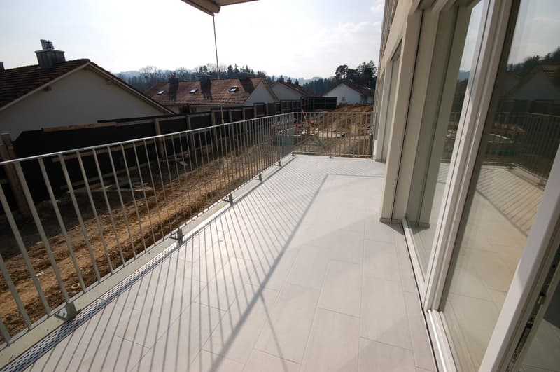 Balcony with white tiled floor, metal railing, and view of neighboring houses and construction area.