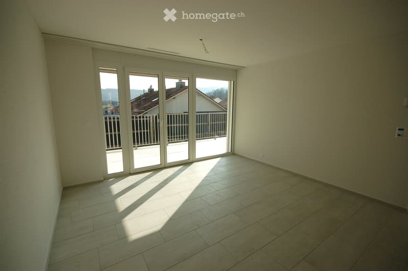 Empty room with tiled floor and large sliding glass doors leading to a balcony. Natural light streams in, casting shadows on the floor.