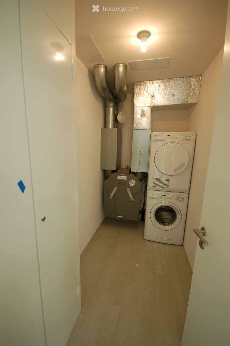 Small utility room with a washing machine, dryer, and boiler, featuring tiled flooring and white walls.