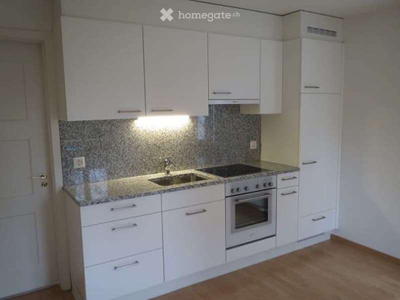 Modern kitchen with white cabinets, granite countertop, sink, stove, and oven.