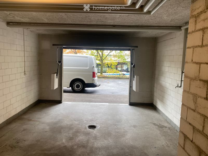 {"type": "Garage", "objects": [], "description": "Underground garage with concrete floor, brick walls, and an open doorway leading to an outdoor parking area where a white van is parked.", "localized_descriptions": {"EN": "Underground garage with concrete