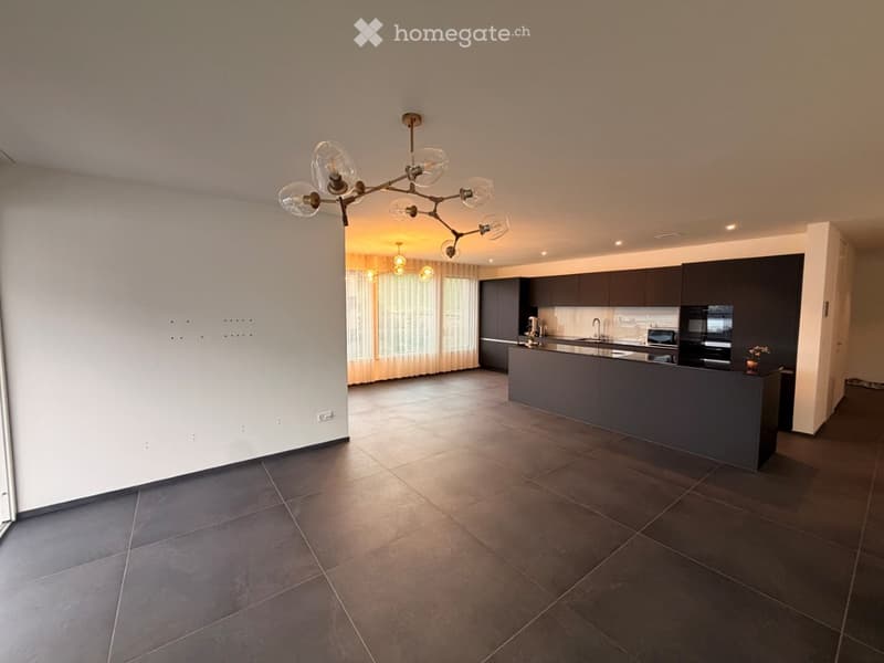 Modern kitchen with dark cabinets, a central island, and a chandelier with multiple glass shades.