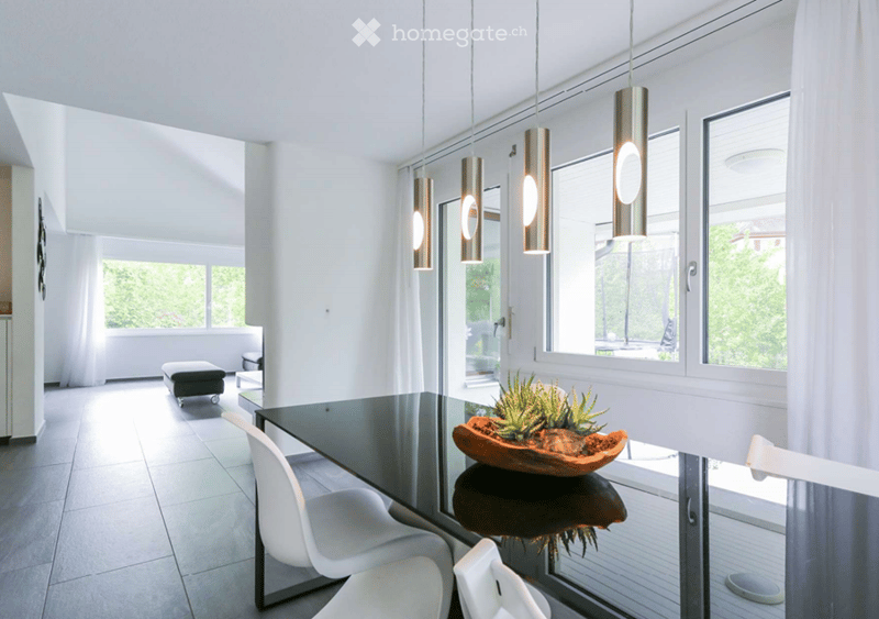 glass and metal table, white chairs, hanging pendant lights, white walls, tiled floor, large windows, balcony, potted plant