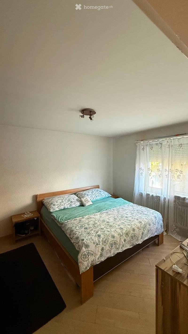 Bedroom with a wooden bed, nightstand, and window with curtains.