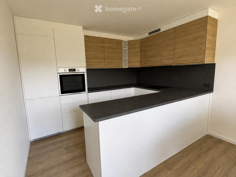 Modern kitchen with white and wooden cabinets, black countertop, and built-in oven.