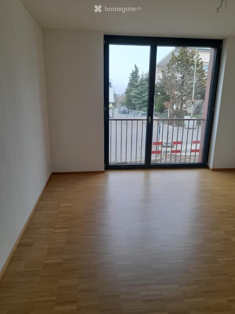 Empty room with wooden flooring and large sliding glass door leading to a balcony area.