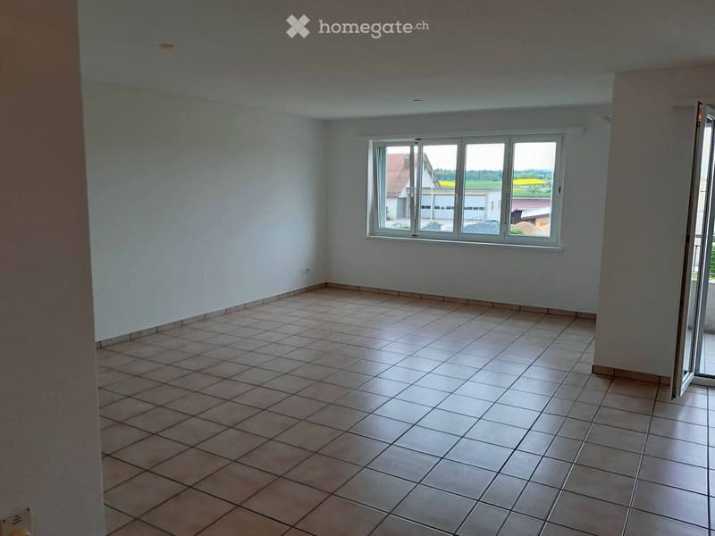 Empty room with tiled floor and large window offering a view of the outside area.