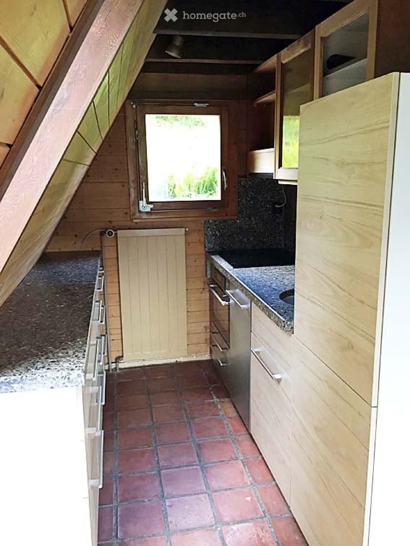 Bright kitchen with wooden cabinets, granite countertop, and stainless steel appliances. Features a large window and tiled floor.