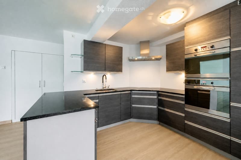 Modern kitchen with dark wood cabinets, stainless steel appliances, and a black countertop.
