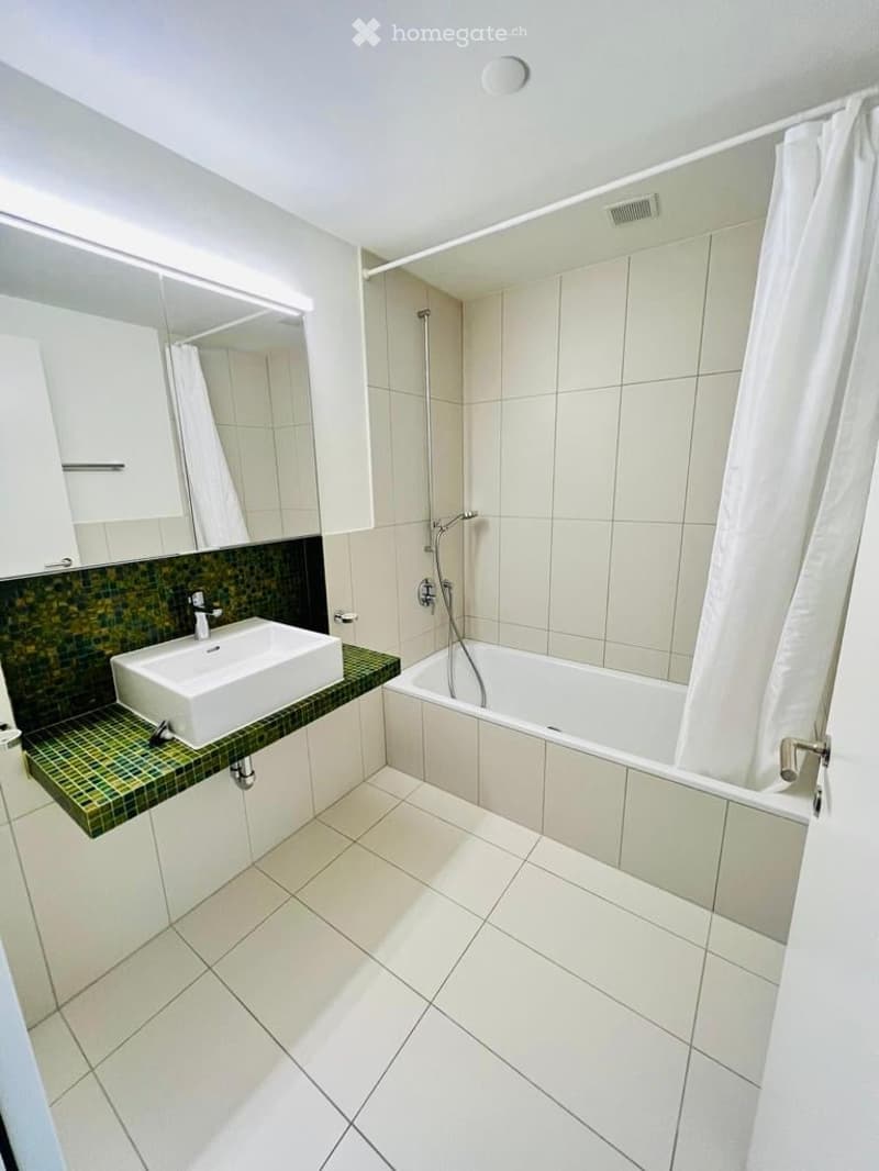 modern bathroom with white tiles, green countertop, white sink, bathtub, shower curtain, mirror, and white cabinets