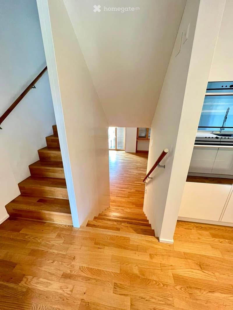 wooden stairs, wooden floor, white walls, kitchen area